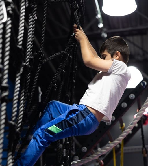 a kid climbing on a rope wall at a ninja fit club near me in londonderry